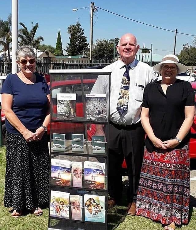 Congregation members standing beside a public Bible literature display.
